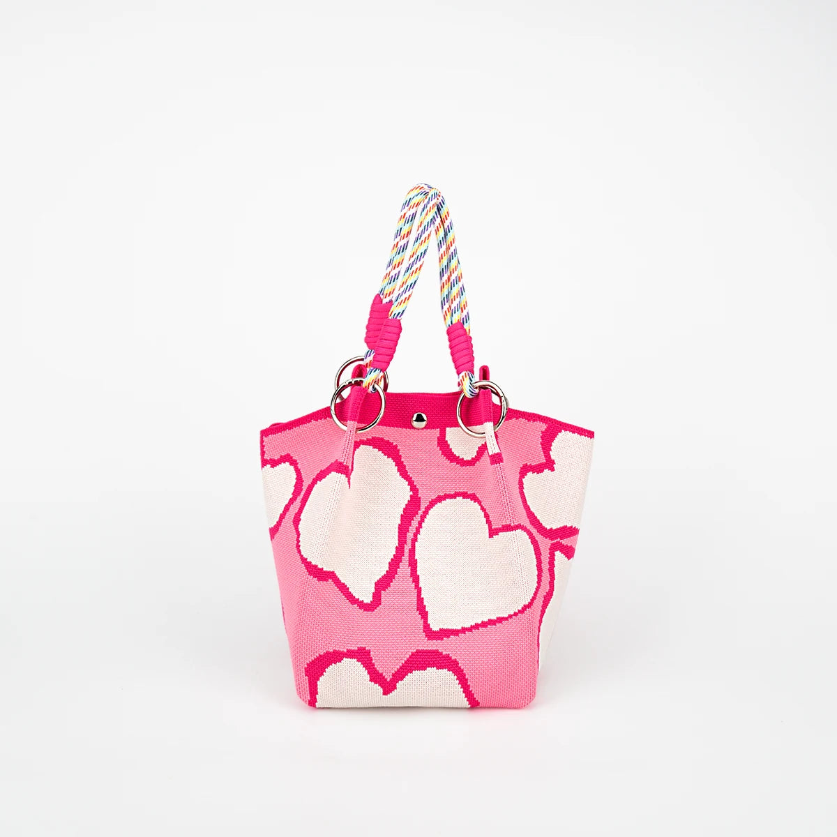 A pink tote bag with a heart print and a multicolored striped rope handle.