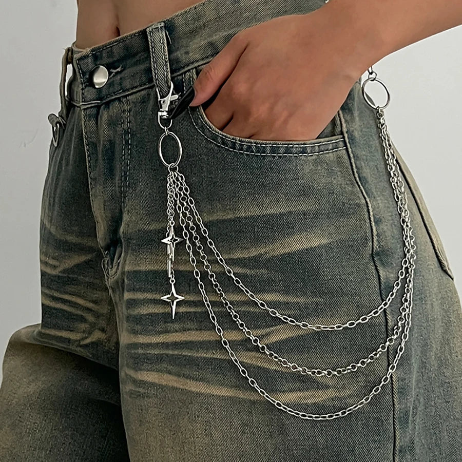 A close-up of a dark wash denim jean pocket featuring a silver punk star chain belt with pearl accents.