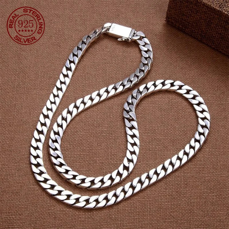A silver chain bracelet with a padlock clasp is displayed on a brown fabric background.