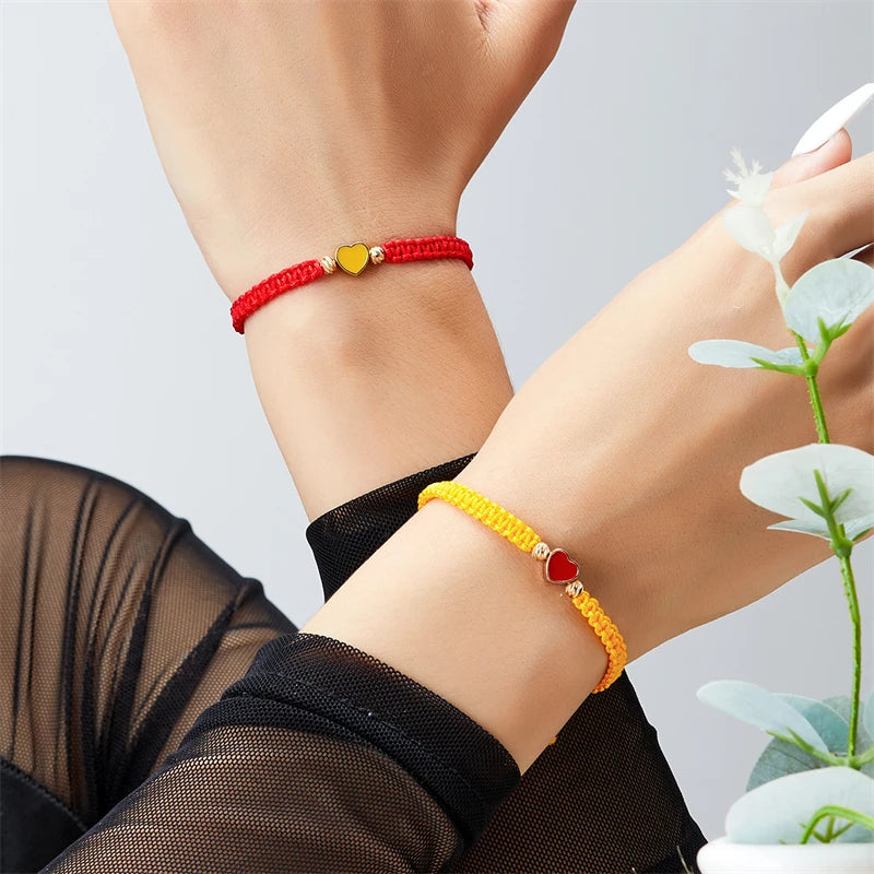 A close-up of two beaded friendship bracelets, one red and one yellow, worn on wrists.