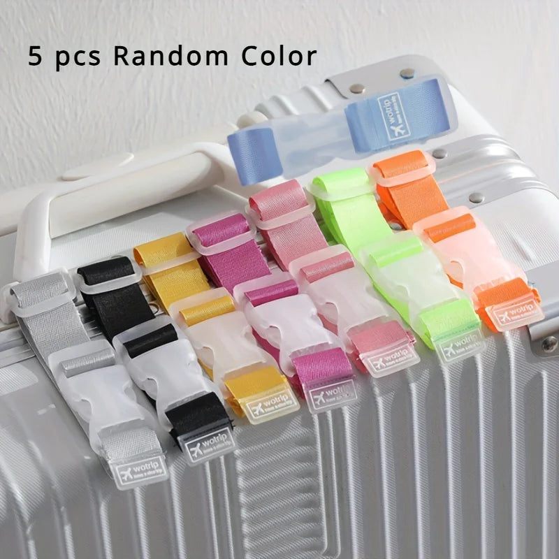 Five random colored adjustable luggage straps with buckles displayed on a white suitcase.
