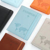 A collection of leather and silicone passport organizers in various colors, including blue, orange, black, and beige.