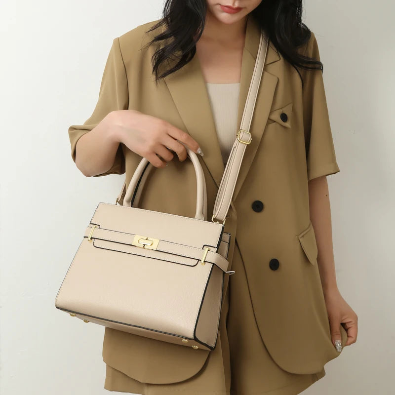 A woman wearing a beige blazer holds a light beige luxury handbag.