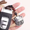 A hand holds a silver and black key ring keychain featuring a detailed cat design and beaded chain.