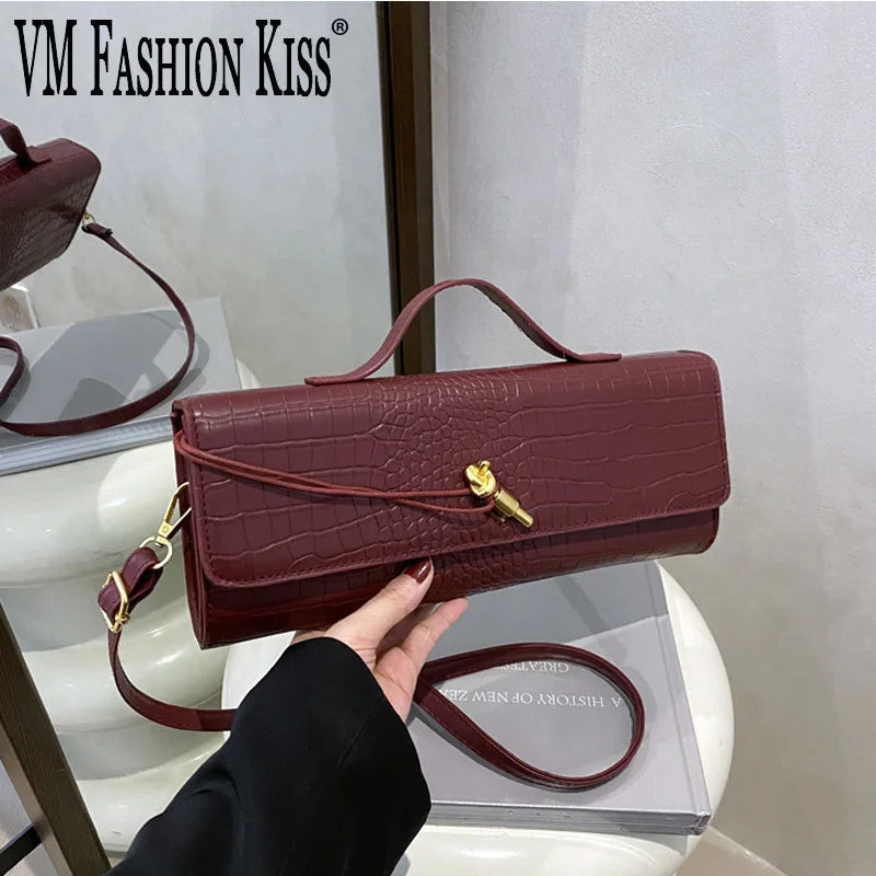 A burgundy crocodile-embossed PU leather clutch bag is being held by a person against a white background.