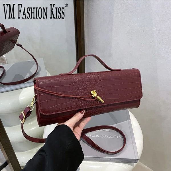 A burgundy crocodile-embossed PU leather clutch bag is being held by a person against a white background.