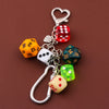 Silver keychain charm featuring various colored dice including red, yellow, white, and green dice.