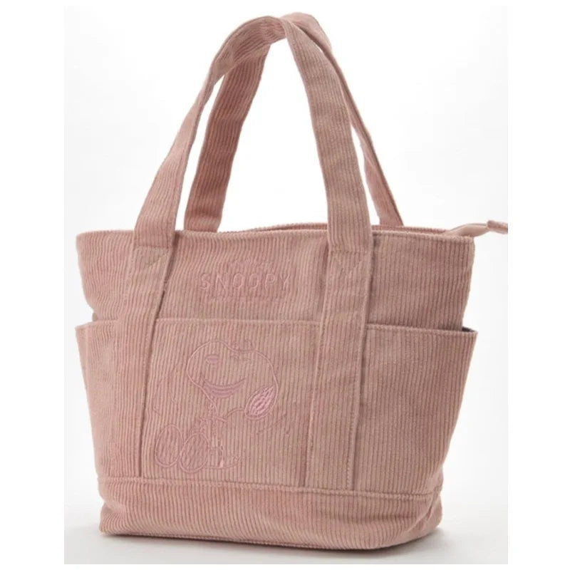 A light pink canvas shoulder bag featuring a Snoopy cartoon design.