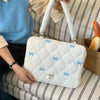 Bolso para portátil acolchado blanco con detalles de lazo azul claro sobre una superficie a rayas.