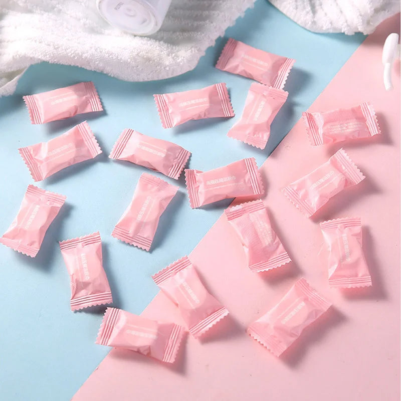 Serviettes faciales en coton compressées roses, éparpillées sur un fond bleu clair et rose.
