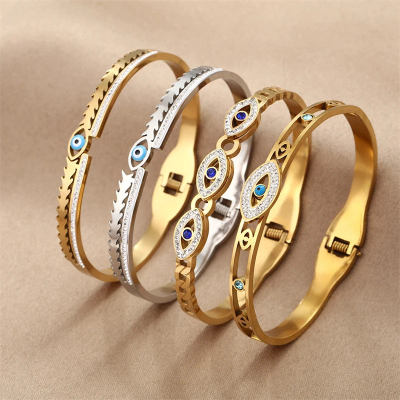 A display of four gold and silver cuff bracelets featuring various evil eye crystal designs.
