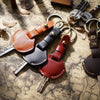 A collection of genuine leather key fob covers and keychains scattered on aged paper.