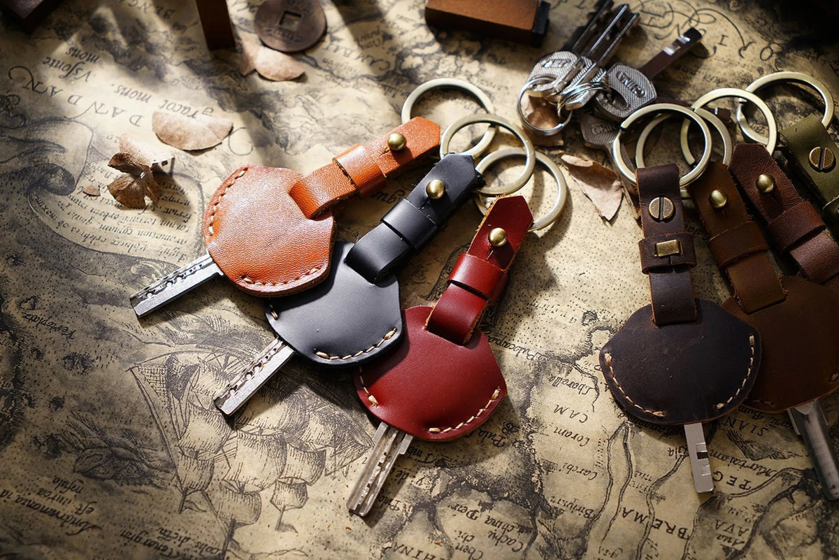 A collection of genuine leather key fob covers and keychains scattered on aged paper.