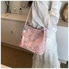 Bolso de seda jacquard rosa con bordado floral llevado por una persona con vestido de encaje blanco.