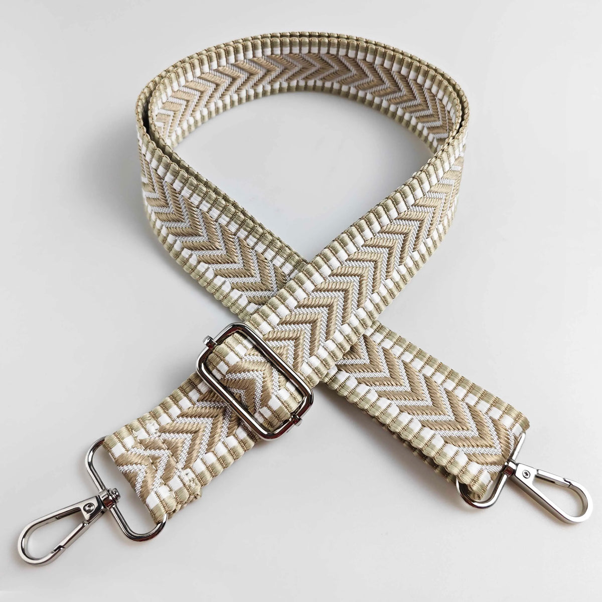 A beige woven handbag strap with an arrow jacquard pattern, shown in an 'X' shape.