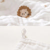 A close-up of a white muslin baby burp cloth towel featuring a cute lion face print.