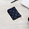 A dark blue zippered card holder wallet with a repeating light gray logo pattern resting on a light wooden surface next to a 