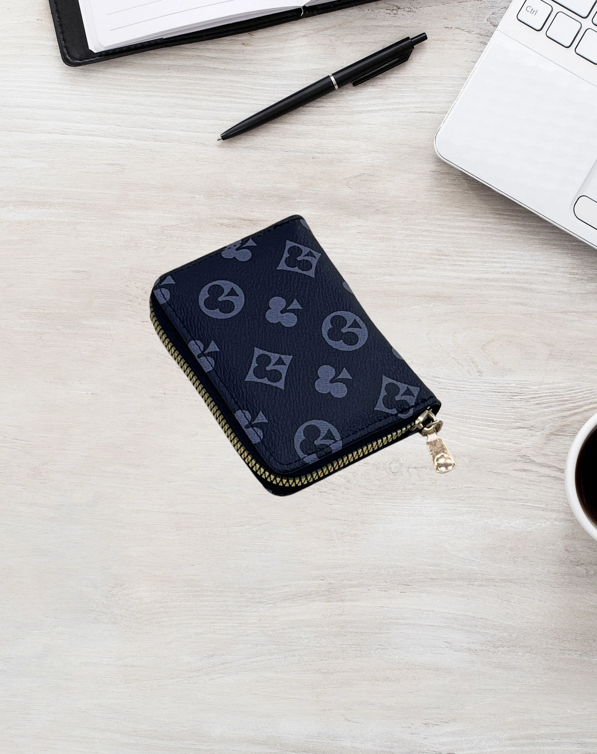 A dark blue zippered card holder wallet with a repeating light gray logo pattern resting on a light wooden surface next to a 