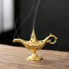 A golden antique metal incense burner with smoke rising on a wooden surface.
