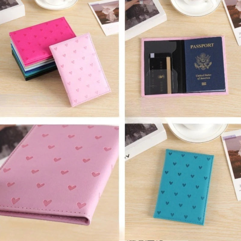 A collection of heart print passport covers and a teal wallet on a wooden surface.