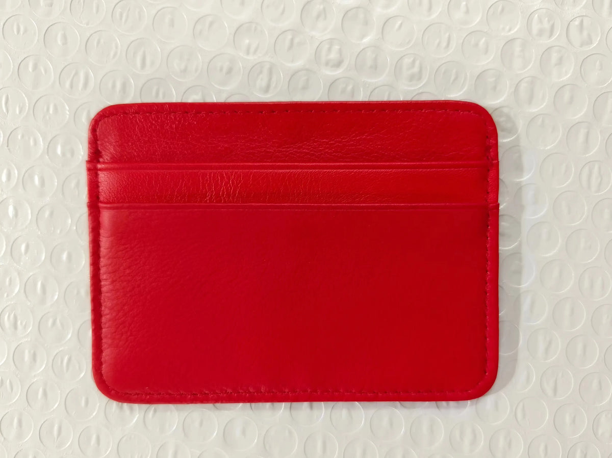 Leuchtend rotes echtes Kuhfell-Kartenschlüsselhalter-Wallet auf weißer strukturierter Oberfläche