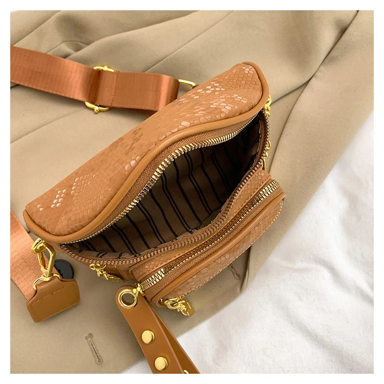 A tan leather women's rivet waist bag crossbody fanny pack with gold hardware shown against a beige fabric background.