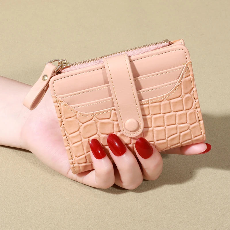 A hand holds a light pink PU leather card wallet with a quilted pattern and double zip closure.