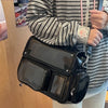A person is holding a black transparent PU crossbody bag with a pink strap, worn over a striped shirt.