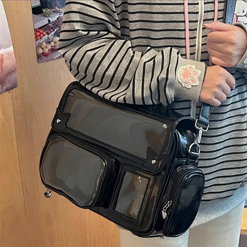 A person is holding a black transparent PU crossbody bag with a pink strap, worn over a striped shirt.