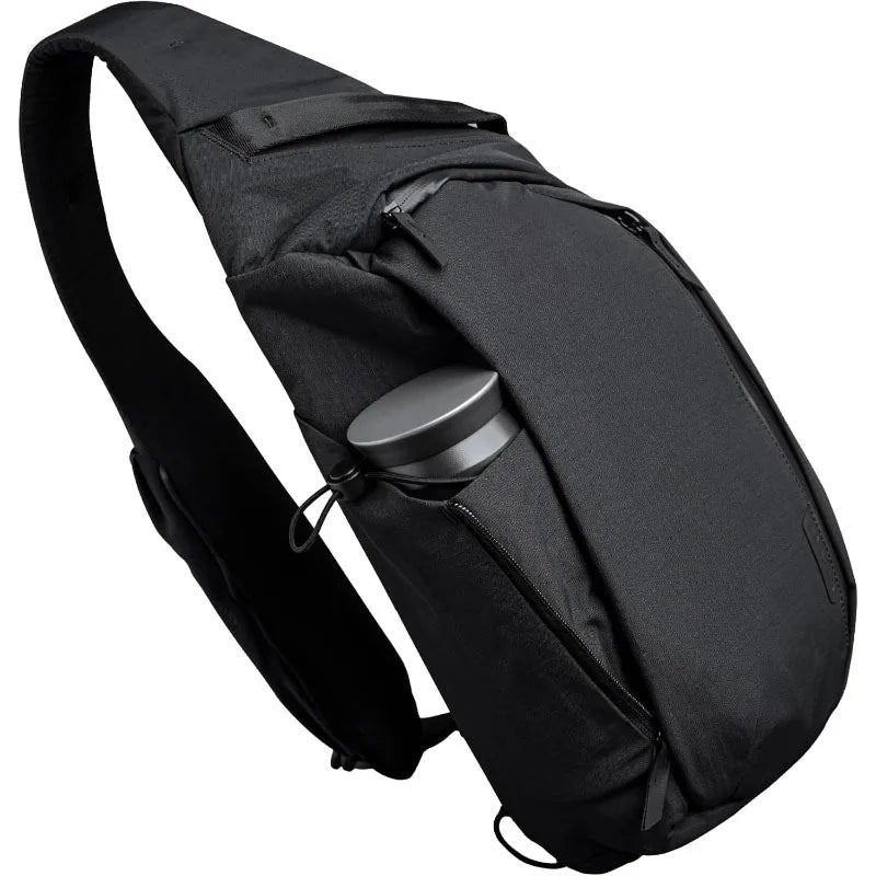Black crossbody sling bag designed to carry a tablet and water bottle.