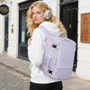 A blonde woman wearing a white hoodie holds a light purple 15-inch travel laptop backpack outdoors.