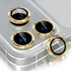 A set of four gold-framed camera lens protectors with black glass covers resting on a silver surface.