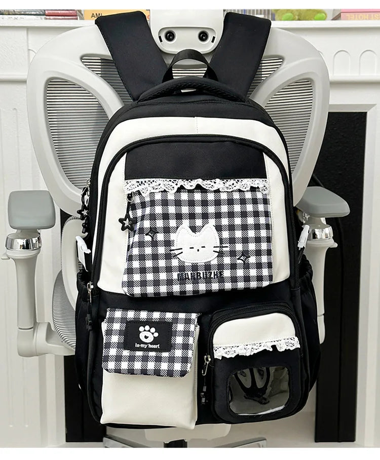 A black and white patterned backpack hanging on a white coat rack.