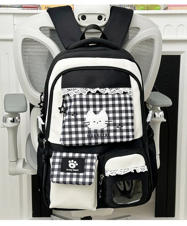 A black and white patterned backpack hanging on a white coat rack.