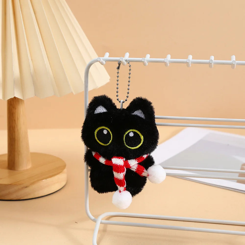 A cute black plush cat keychain charm hanging on a wire rack.
