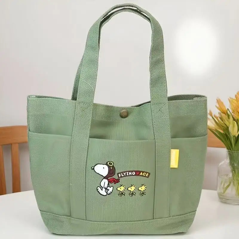 A light green canvas shoulder bag featuring a Snoopy cartoon design.