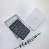 A black geometric print passport wallet is displayed next to its white packaging box on a white surface.