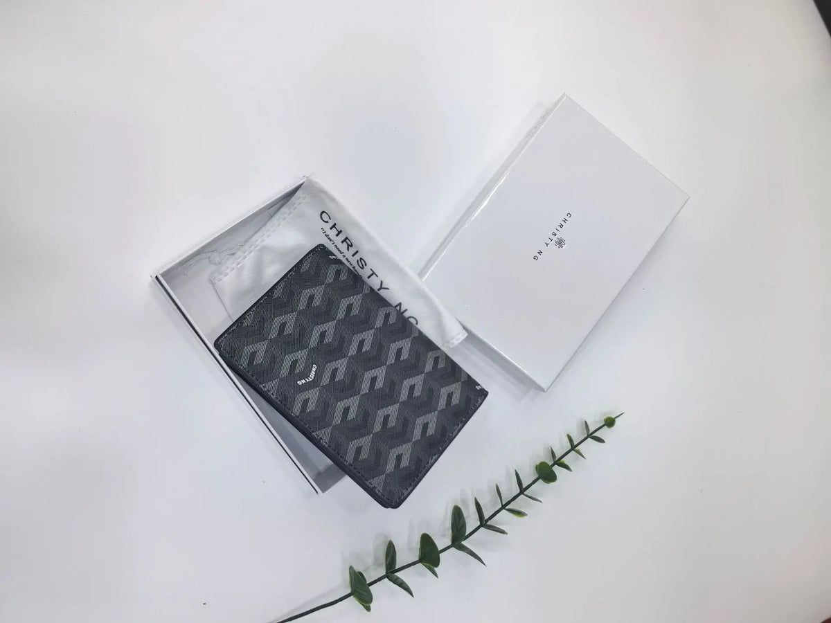 A black geometric print passport wallet is displayed next to its white packaging box on a white surface.