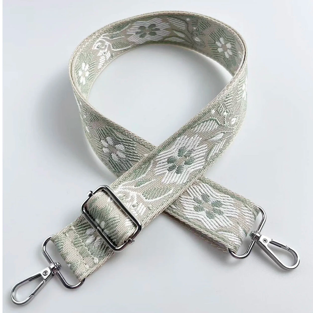 A beige patterned fabric strap with silver hardware, used as a crossbody bag strap.