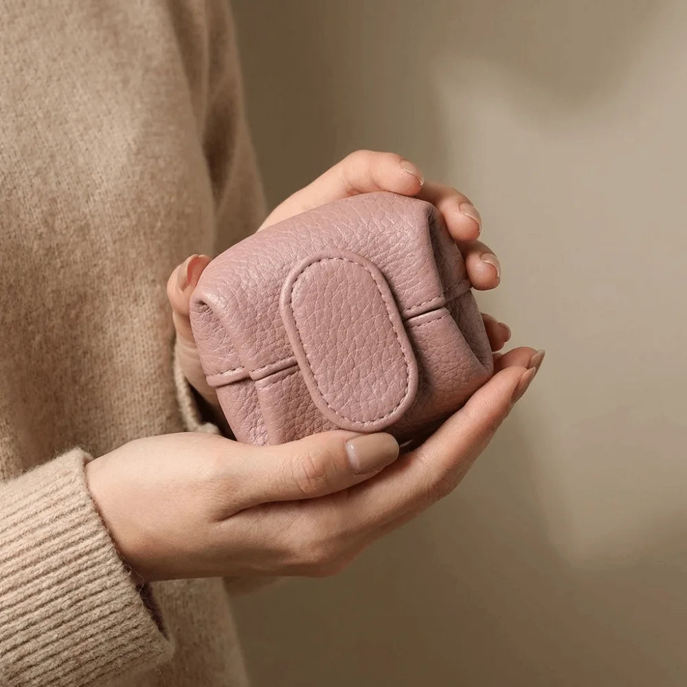 A person is holding a pink lychee-textured coin purse with a snap closure against a neutral background.