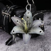 A realistic silver-gray orchid flower keychain attached to a black leather bag.