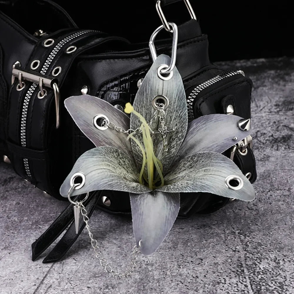 A realistic silver-gray orchid flower keychain attached to a black leather bag.