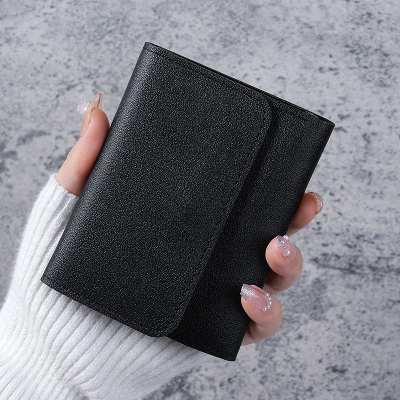 A hand holds a black slim multi-functional card wallet against a gray background.