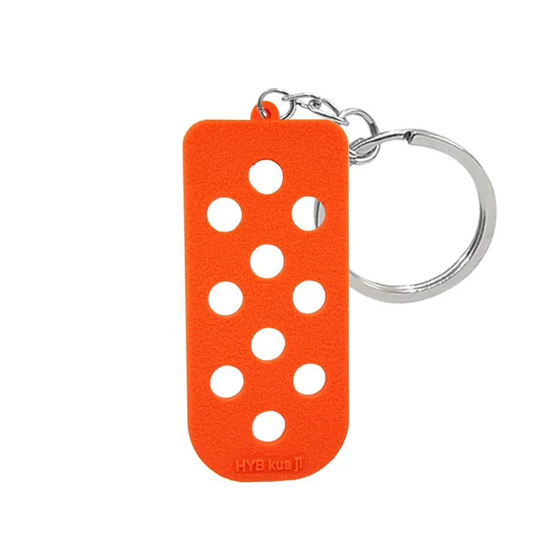 Porte-clés avec un charme en silicone orange et un anneau à sertir argenté.
