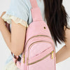 Un sac bandoulière matelassé rose avec une sangle rose porté par une personne en haut bleu clair.
