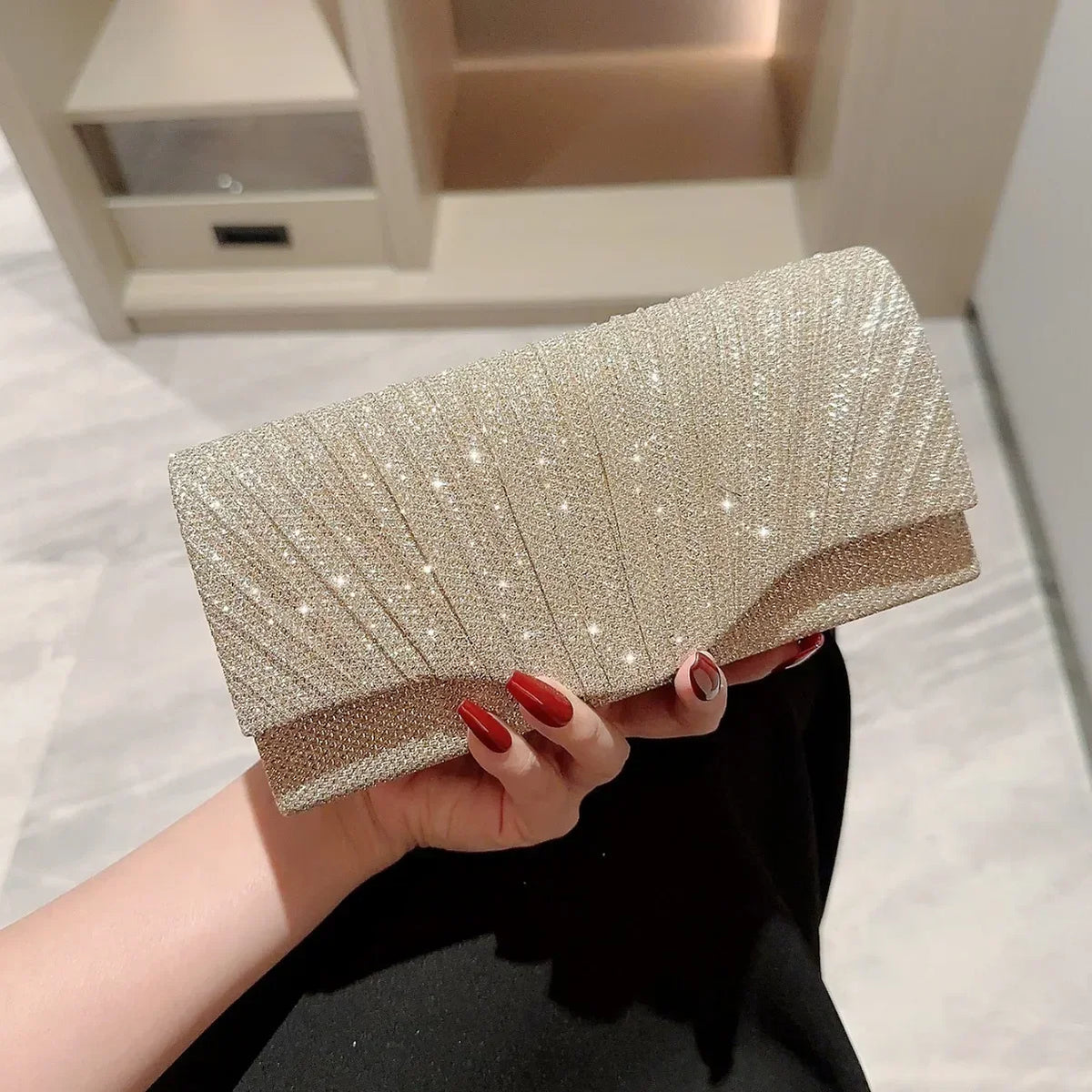 Eine Hand hält eine elegante silberne Halskette als Schultertasche mit texturierter, funkelnder Oberfläche.