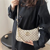Una mujer sostiene un bolso cruz de mano vintage dorado con monograma blanco y gris.