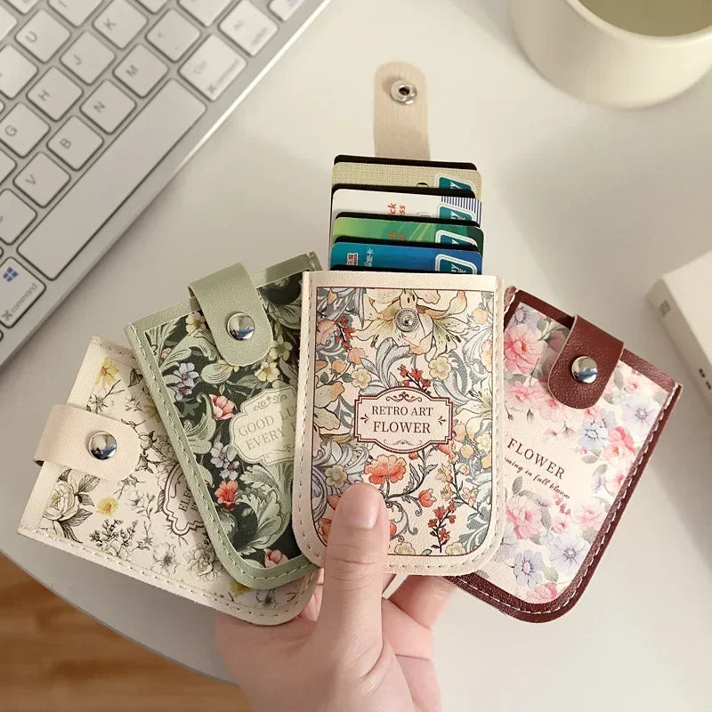 A hand holds a stack of pastel floral PU card wallets in various shades and colors on a white surface.