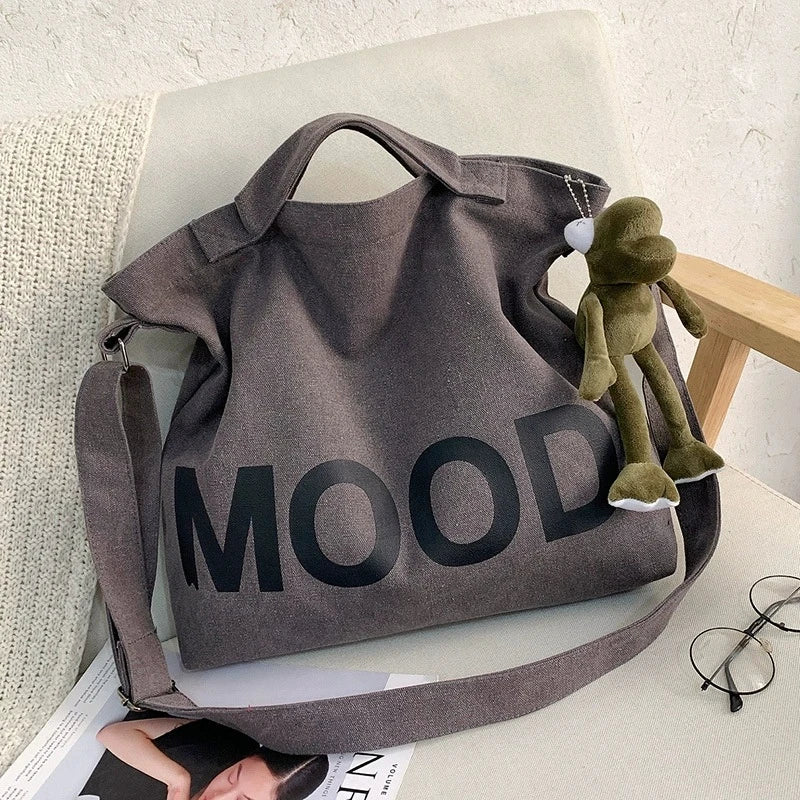 A dark gray canvas tote bag featuring the word MOOD printed in black text, resting on a light surface.