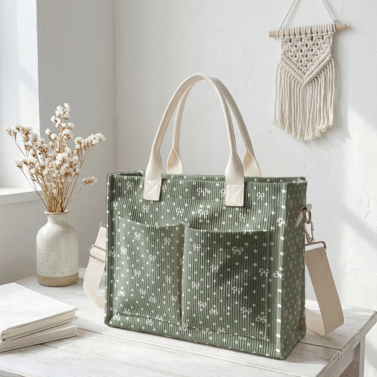 Un sac en corduroy vert à pois roses accroché à un mur blanc.